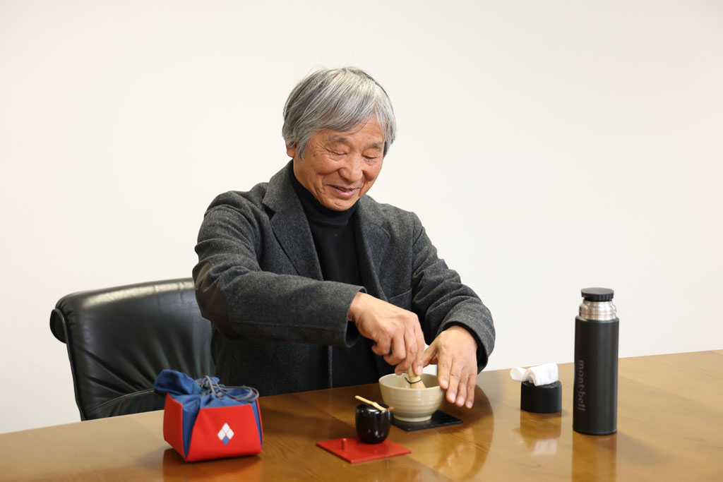 小さめの茶碗、棗（なつめ）、茶筅、茶杓（しゃく）などの「アウトドア野点セット」で点茶する辰野氏。不整地で野点をすることが多いので、棗を置いた赤い盆に茶筅を立てる小さな棒が付いている