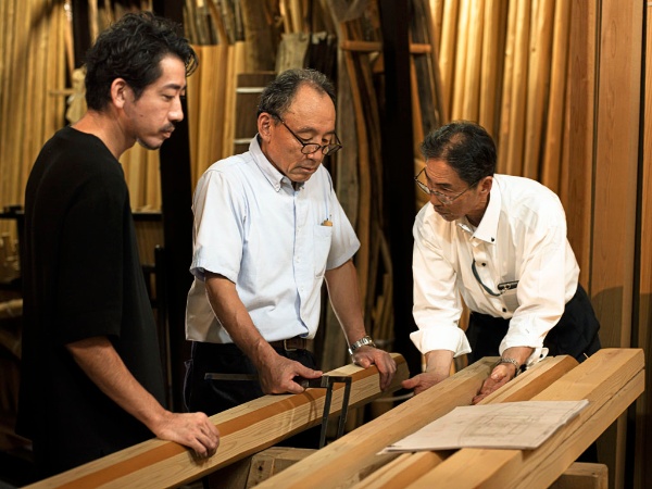 キャンパス内に建設中の茶室に使う木材(北山杉磨丸太の面皮柱)について、面(ツラ)の付け方を検討しているところ。写真左から、建築家の三井嶺氏、北山杉を育てている銘木の生産者、数寄屋大工の棟梁 写真提供/伊藤穰一氏