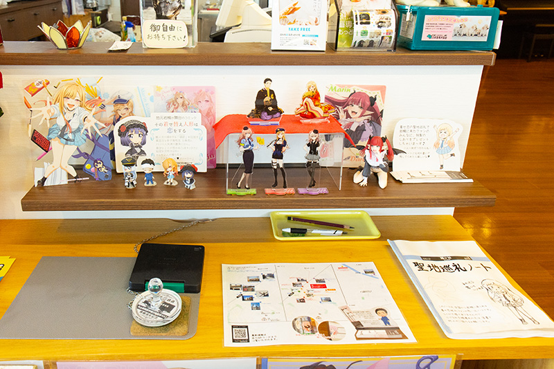 『その着せ替え人形は恋をする』聖地巡礼マップと聖地巡礼ノート。ファンが持ち込んだキャラクターのアクリルスタンドもある