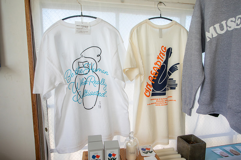 太宰治の小説の一節が描かれたTシャツ（左）とON READINGのオリジナルTシャツ