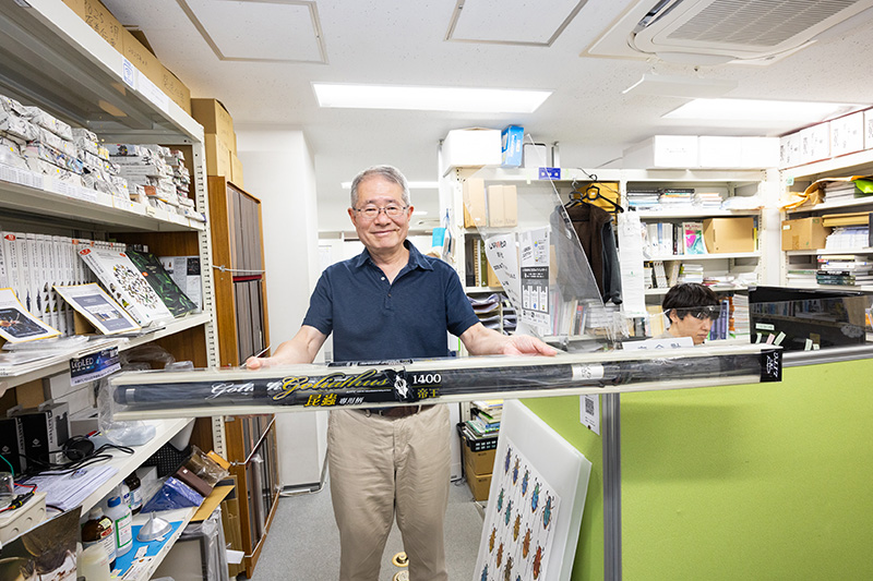 昆虫採集の竿を持つ川井さん。「売れ筋は8メートルや14メートルなど長いもの」