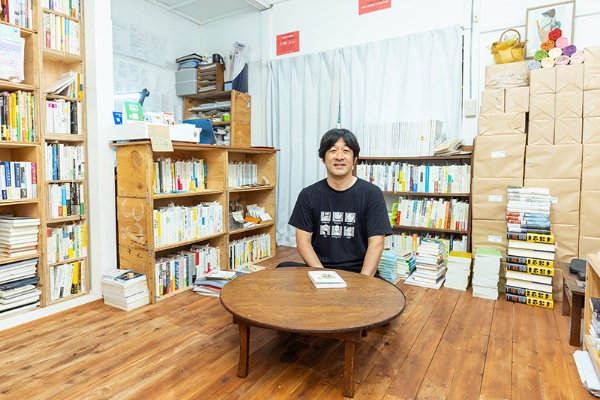 小上がりのちゃぶ台と小谷さん。「お客さんが来ないときには、ここで寝てしまうこともあります」 小上がりのちゃぶ台と小谷さん。「お客さんが来ないときには、ここで寝てしまうこともあります」