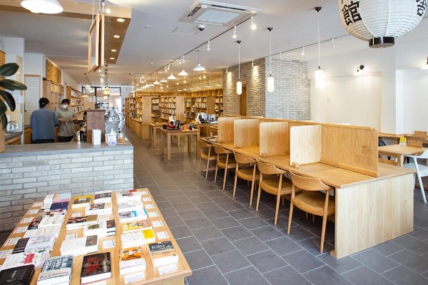 手前が喫茶スペースと企画本の展示。奥に書籍や雑誌、雑貨が並ぶ 手前が喫茶スペースと企画本の展示。奥に書籍や雑誌、雑貨が並ぶ