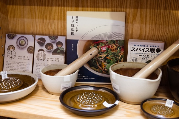 すり鉢とおろし器の後ろに、すり鉢料理とスパイスの本が並ぶ すり鉢とおろし器の後ろに、すり鉢料理とスパイスの本が並ぶ
