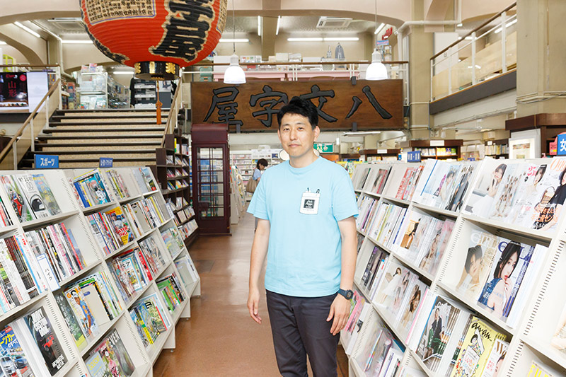 雑誌棚の前に立つ東根智広さん。「雑誌は本の売り上げの約3割を占めており、今も大切なジャンルです」 雑誌棚の前に立つ東根智広さん。「雑誌は本の売り上げの約3割を占めており、今も大切なジャンルです」