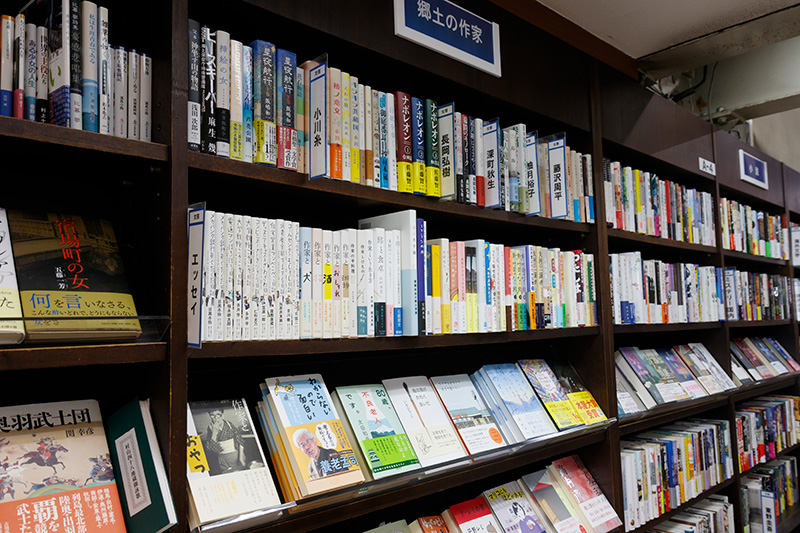 郷土の作家のコーナー。小川糸、長岡弘樹、深町秋生、柚木裕子、藤沢周平などの作品が並ぶ