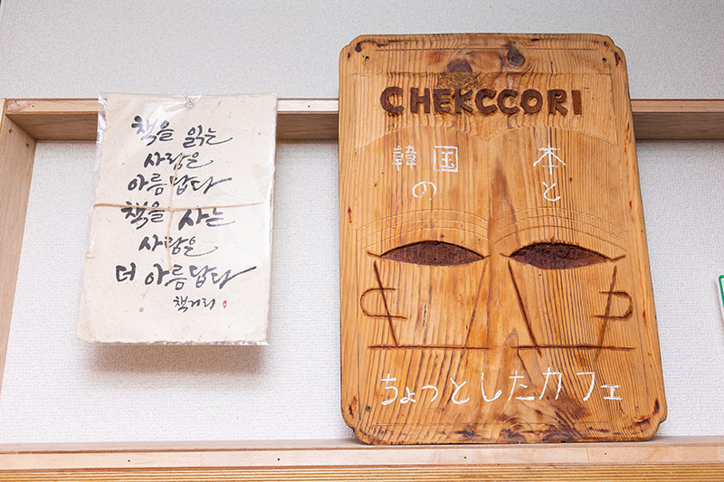 店の入り口の看板。左の色紙には「本を読む人は美しい。本を買う人はもっと美しい」と書かれている