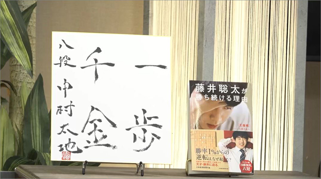 中村八段の色紙と第71期王座戦をまとめた『藤井聡太が勝ち続ける理由 王座戦――八冠の先へ』(日本経済新聞社編、日本経済新聞出版)(写真:2024年4月23日NIKKEI LIVEより) 中村八段の色紙と第71期王座戦をまとめた『藤井聡太が勝ち続ける理由 王座戦――八冠の先へ』(日本経済新聞社編、日本経済新聞出版)(写真:2024年4月23日NIKKEI LIVEより)
