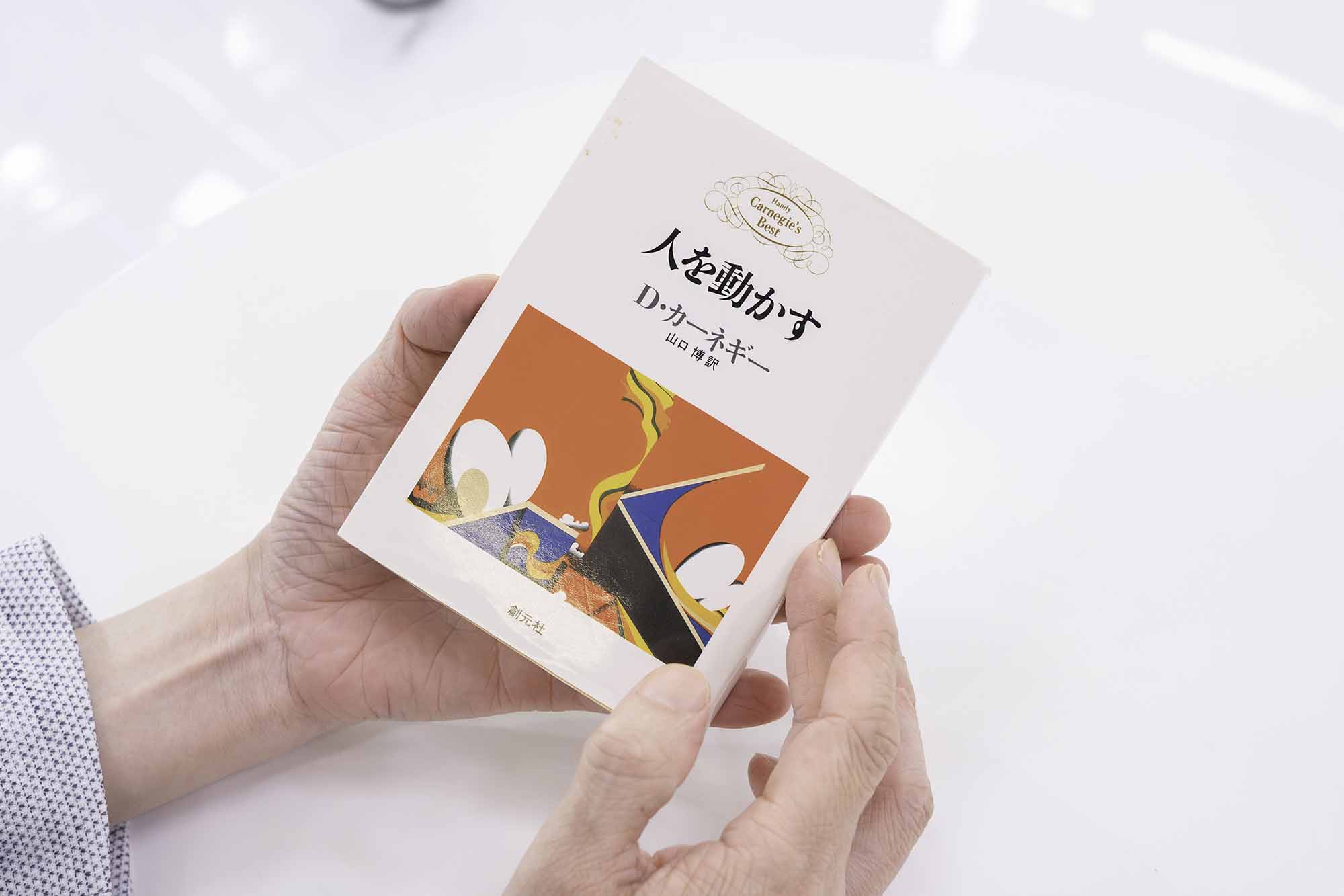 写真は、平石さんの本棚から持ってきてくれた、何度も読み返している私物の『人を動かす』(D・カーネギー著、山口博訳、創元社)/画像クリックでAmazonページへ