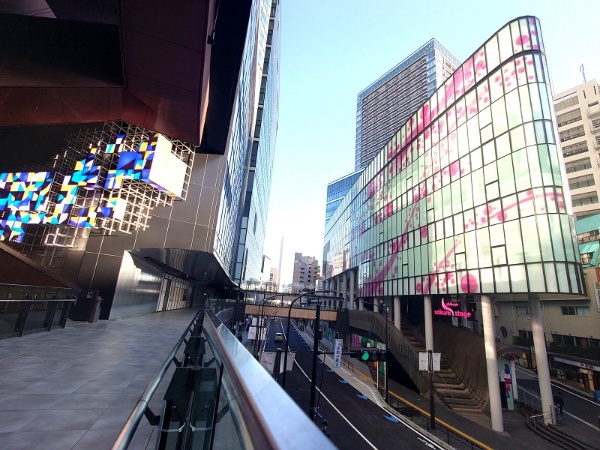 SAKURAサイドの先端部で、駅寄りに立つ「SAKURAテラス」(写真右手)。桜のデザインを取り入れた曲面の外観が特徴の建物で、中はテラスのような歩行者空間と商業施設になる。外装の桜模様が動いているように見える「キネティック・ファサード」を採用(写真:日経クロステック)
