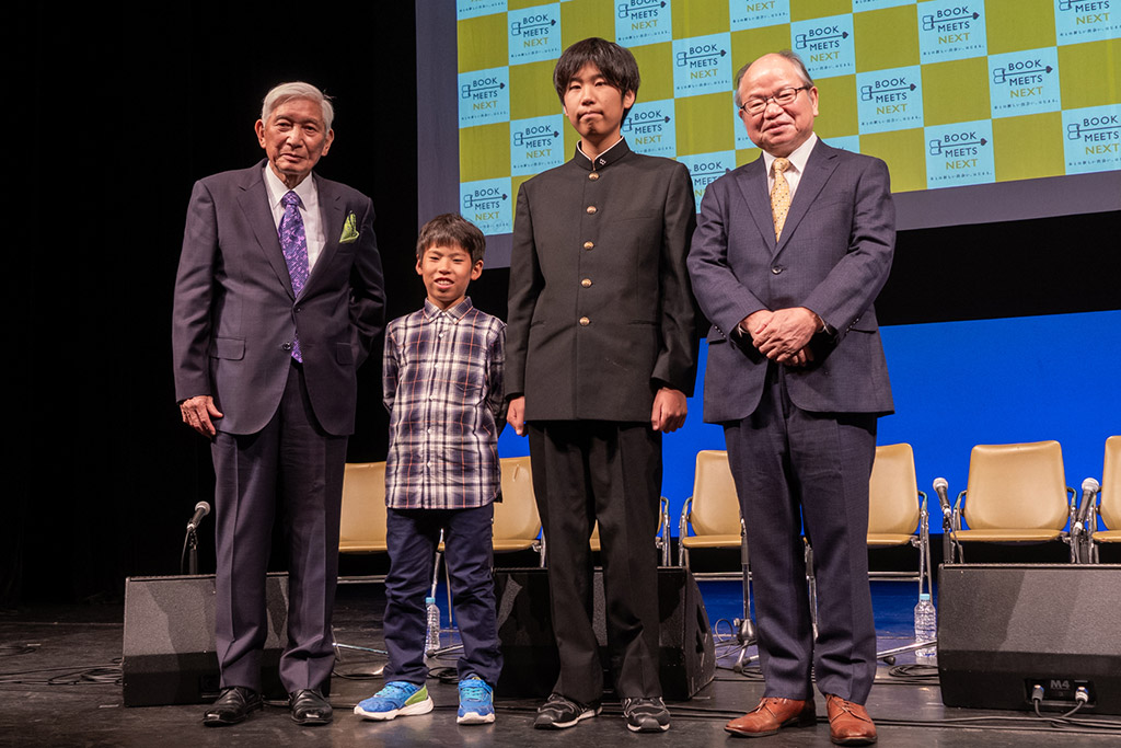 「秋の読書推進月間」オープニングイベントで壇上に立った運営委員会委員長の高井昌史氏（紀伊國屋書店会長）、「地球さんご賞」を受賞した小学校5年生の桶谷樹志さんと高校1年生の吉田孝太さん、そして「地球さんご賞」実行委員長で作家の安部龍太郎氏（写真左から順に）