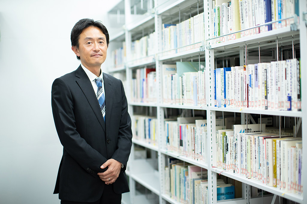 日本総合研究所 マクロ経済研究センターにある書庫に立つ西岡慎一さん