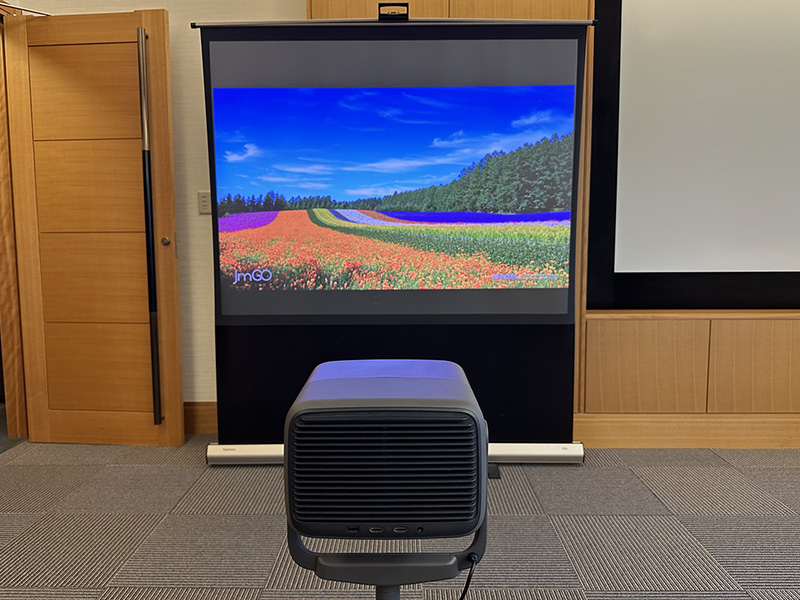 レーザープロジェクターとその映像。日亜化学工業は、レーザープロジェクター用窒化ガリウム（GaN）系高出力半導体レーザーで100％のシェアを誇っている（2024年時点）。なお、このプロジェクターは中国メーカーの製品。（写真：日経クロステック）
