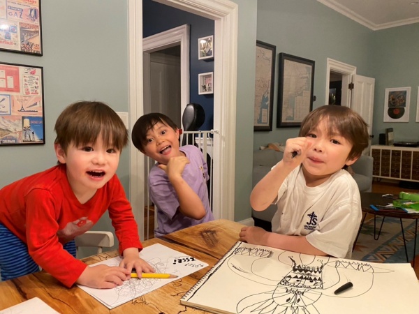 内田さんの3人の子どもたち。みんなが集まる自宅の机でお絵かきをしながら(写真:本人提供)