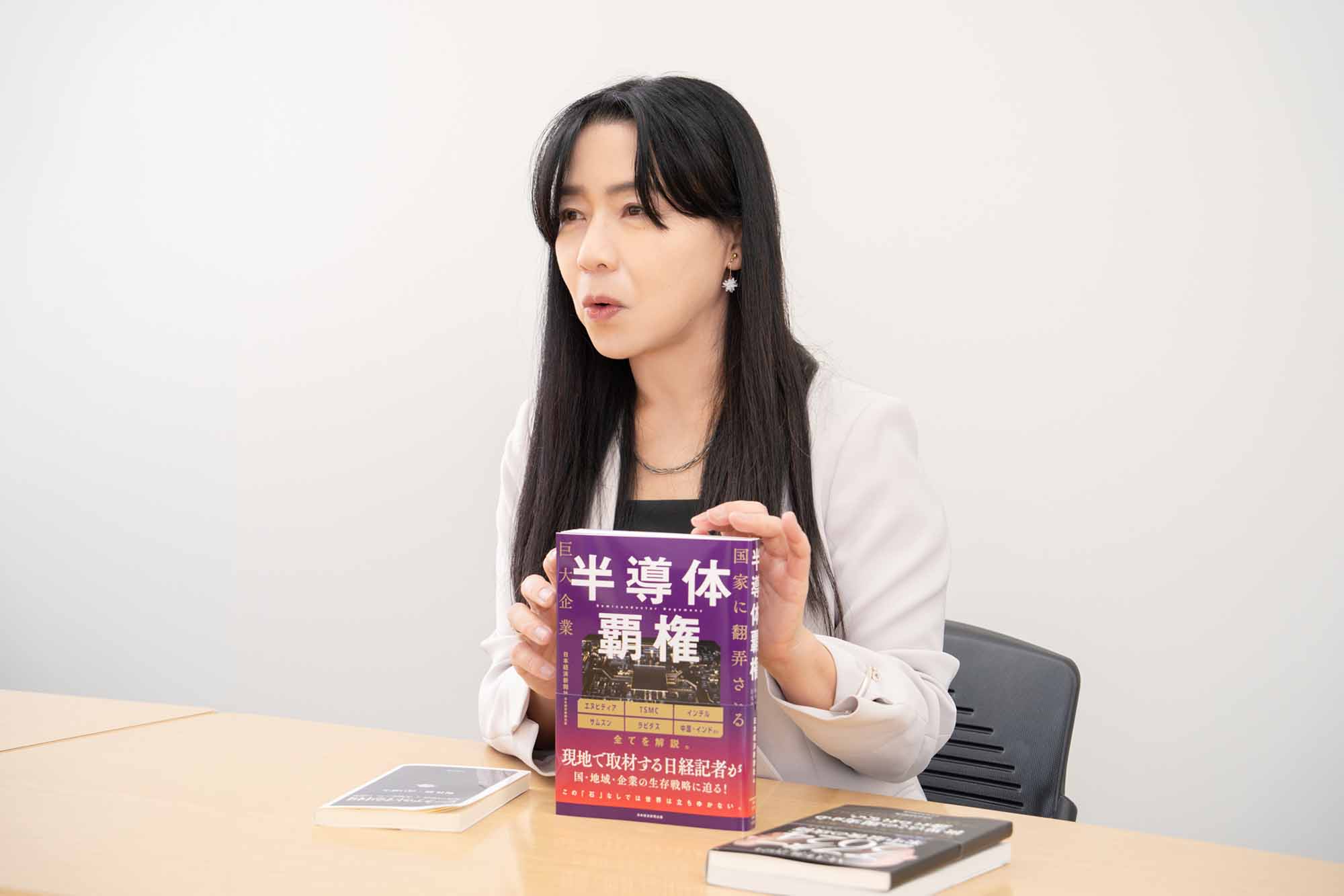『半導体覇権　国家に翻弄される巨大企業』（日本経済新聞社編）を持つ桃井さん。画像クリックでAmazonページへ