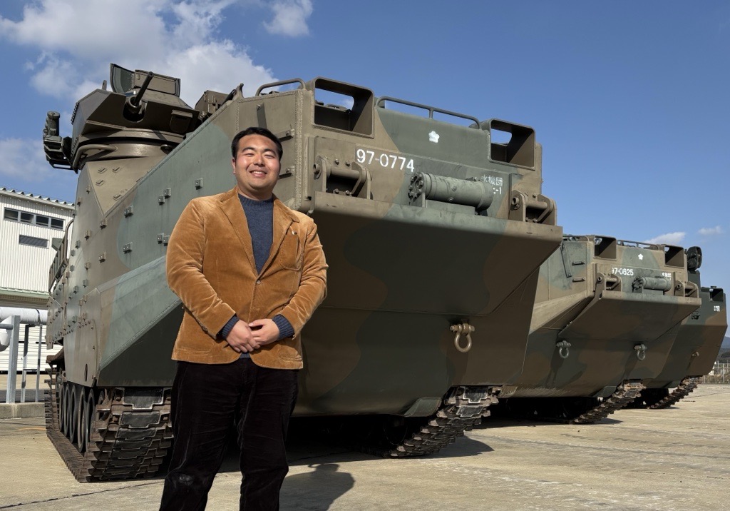 稲葉義泰さん。後方に写っているのは陸上自衛隊の水陸両用装甲車AAV7(稲葉さん提供)
