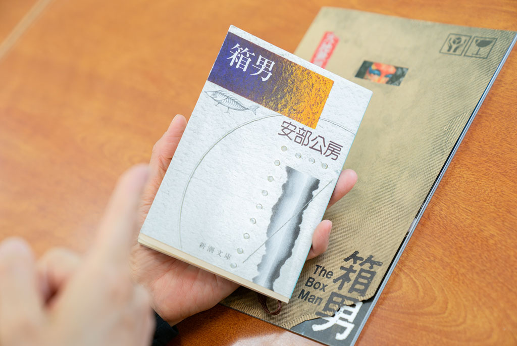 「『箱男』（安部公房著／新潮文庫）は、他者との関係や『自分とは何か』という問いを根底から揺さぶる作品です。大学時代に読んだときの衝撃は、今も忘れられません」（後ろにあるのは、映画『箱男』のパンフレット）