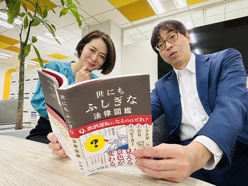 楽しいイラストと分かりやすい解説で構成された『世にもふしぎな法律図鑑』(中村真著)を熱心に読む赤木部長&常陸編集長。どのページを見ているのでしょうか?