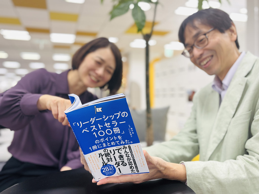 『「リーダーシップのベストセラー100冊」のポイントを1冊にまとめてみた。』（藤𠮷豊、小川真理子著）。ともに現場を率いる赤木部長＆常陸編集長、笑顔でリーダーシップ談義中