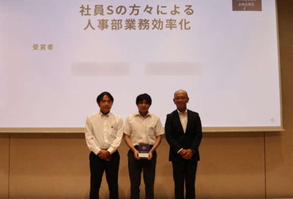 「ブレークスルーアワードDX推進賞」を受賞した職場の社員たち(左の2人)。ポジティブ情動が喚起される職場で、創造性や挑戦意欲を高めた(写真:丸井グループ)