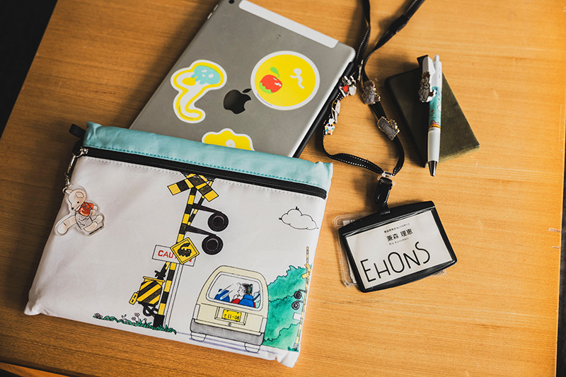 兼森さんのお仕事グッズ。「わかったさん」のポーチに、『こんとあき』のキーホルダー、iPadには『ゲナポッポ』のステッカーが貼ってある。他にも、『ねこまたごよみ』『ねずみくんのチョッキ』などのグッズが。絵本への愛が伝わってくる